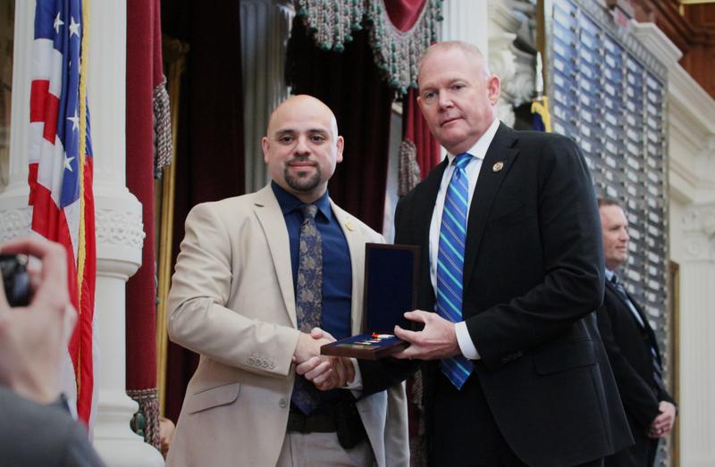 Agent Herrera shakes hands with an official as he receives his award.