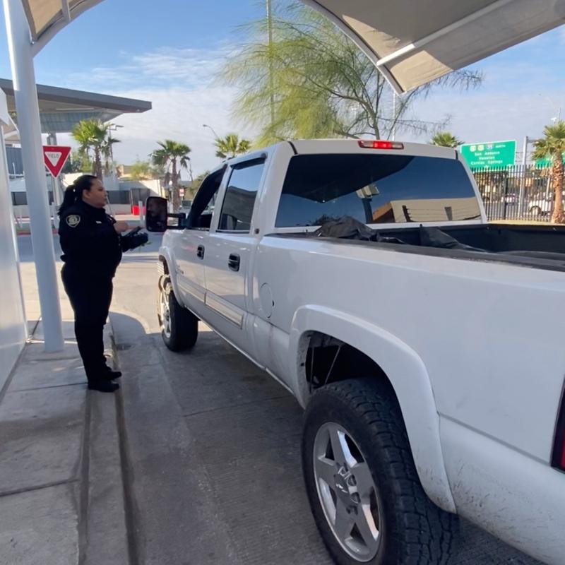 Regulatory compliance officer checking a vehicle at a border inspection station.