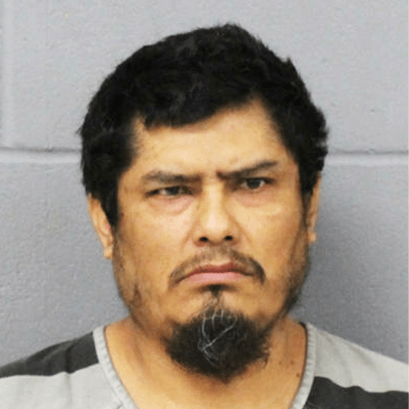Mugshot of suspect, who has black hair and a black and grey goatee. He is wearing a striped jail uniform.